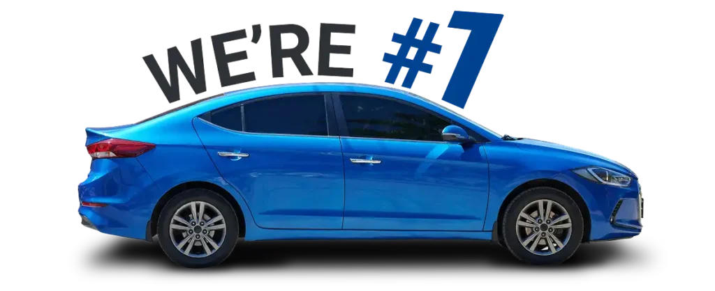 Auto repair shop in Springboro, OH, Springboro Automotive. A blue sedan car is displayed against a black background. Behind the car, large text in varying fonts reads WERE #1 in blue and gray. The car is shown in profile view facing left.