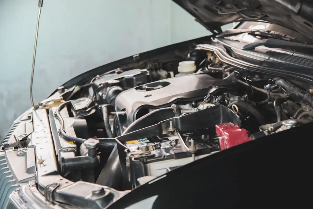 Diesel Repair, Auto repair shop in Springboro, OH, Springboro Automotive. The image shows an open car hood displaying the engine and various components, including the battery and fluid reservoirs. The metal parts are clean, and the setting appears to be a garage or workshop.