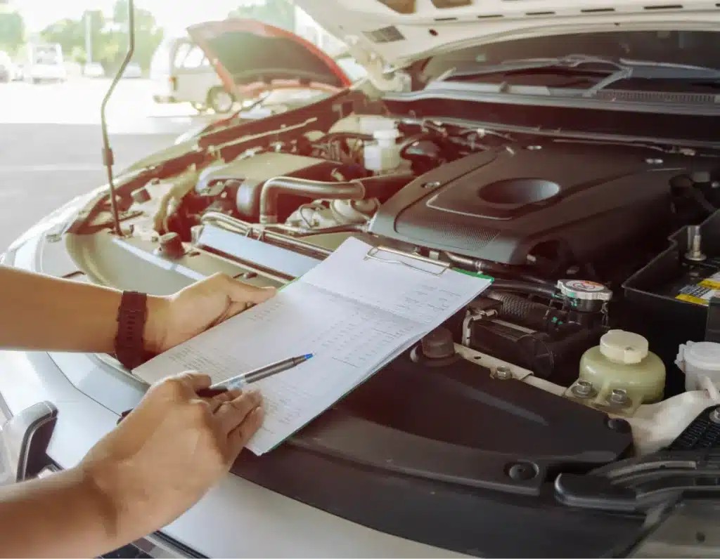 auto engine repair and diagnostics, Auto repair shop in Springboro, OH, Springboro Automotive. Person holding a clipboard and pen, inspecting a car engine, with the car hood open in a bright outdoor setting.