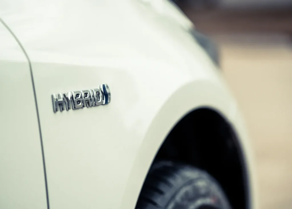 Hybrid car maintenance, Auto repair shop in Springboro, OH, Springboro Automotive. Close-up of a white cars side, focusing on a HYBRID emblem. The angled shot prominently features the emblem and part of the rear tire, highlighting the vehicles eco-friendly design.