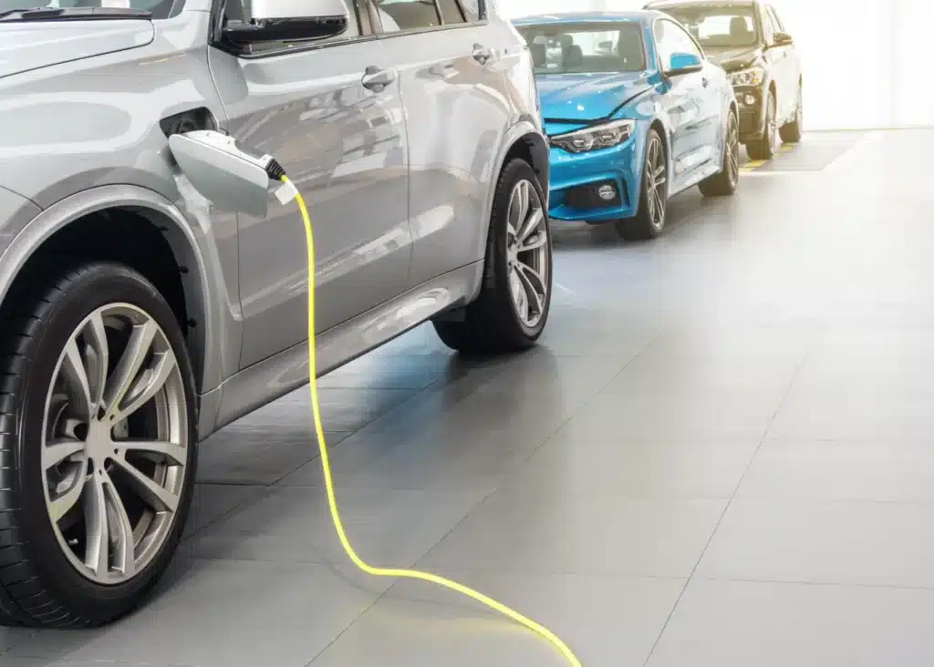 Hybrid car maintenance, Auto repair shop in Springboro, OH, Springboro Automotive. An electric car is plugged in and charging with a yellow cable in a showroom. Several other cars are lined up in the background.